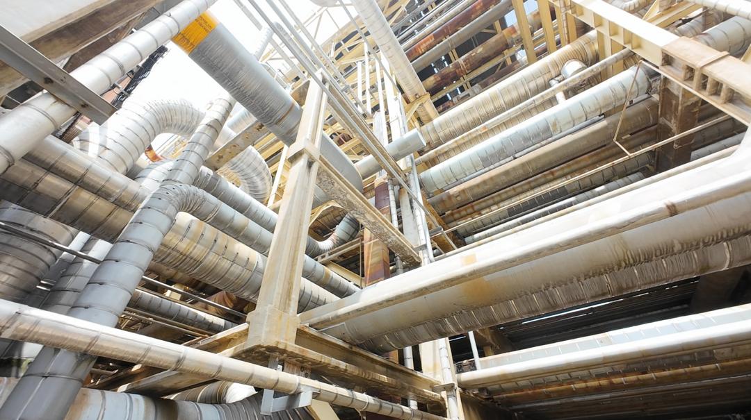 Overhead view inside a dense industrial pipe rack